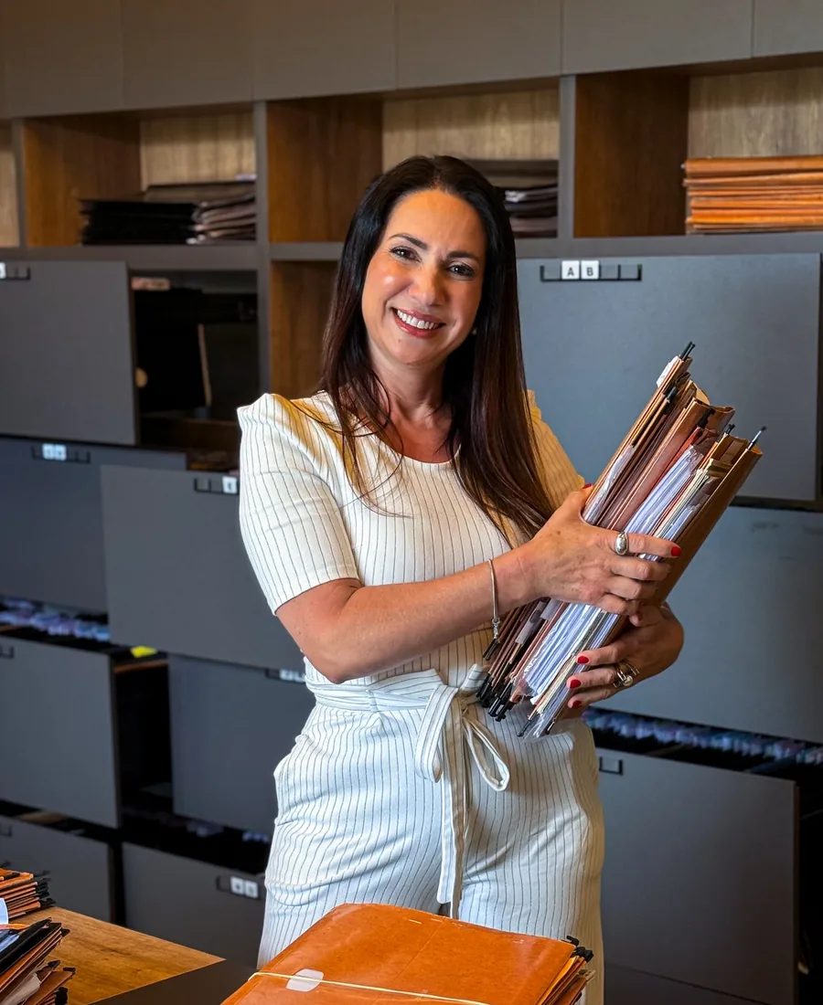 Dra. Andreia Aguilar segurando pastas de processos no escritório